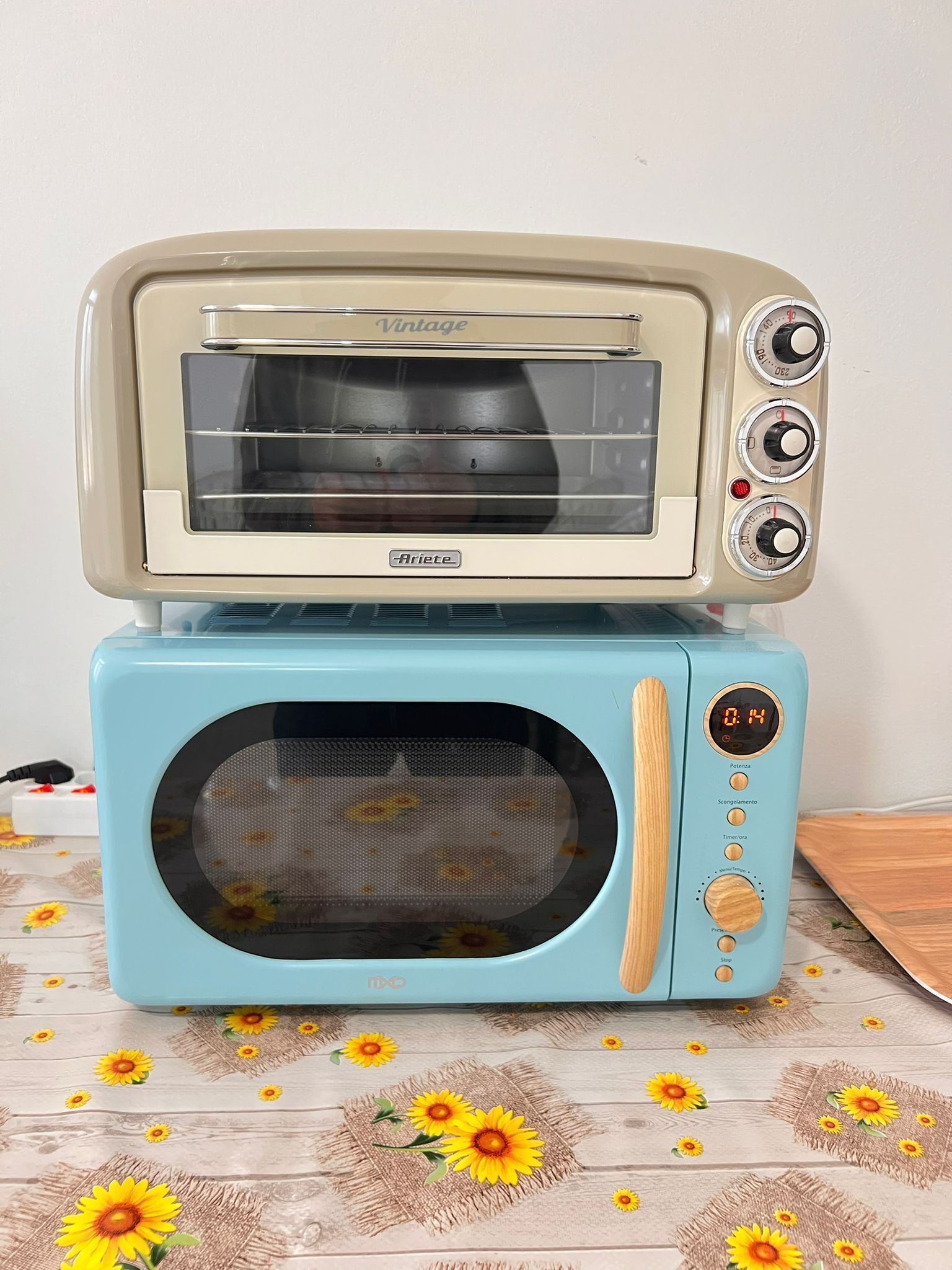Ein Toasterofen im Vintage-Stil mit digitaler Anzeige, platziert auf einer Holzoberfläche mit Sonnenblumenmuster.