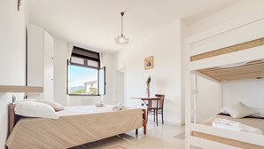 A bedroom with a bed, a desk, and a view of the outside. - Ostello Brebei Niedda (Gonnesa)