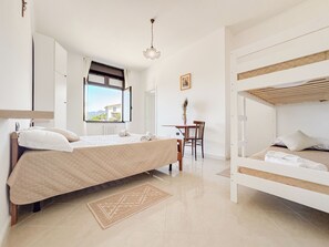 A bedroom with a bed, a desk, and a view of the outside. - Ostello Brebei Niedda (Gonnesa)