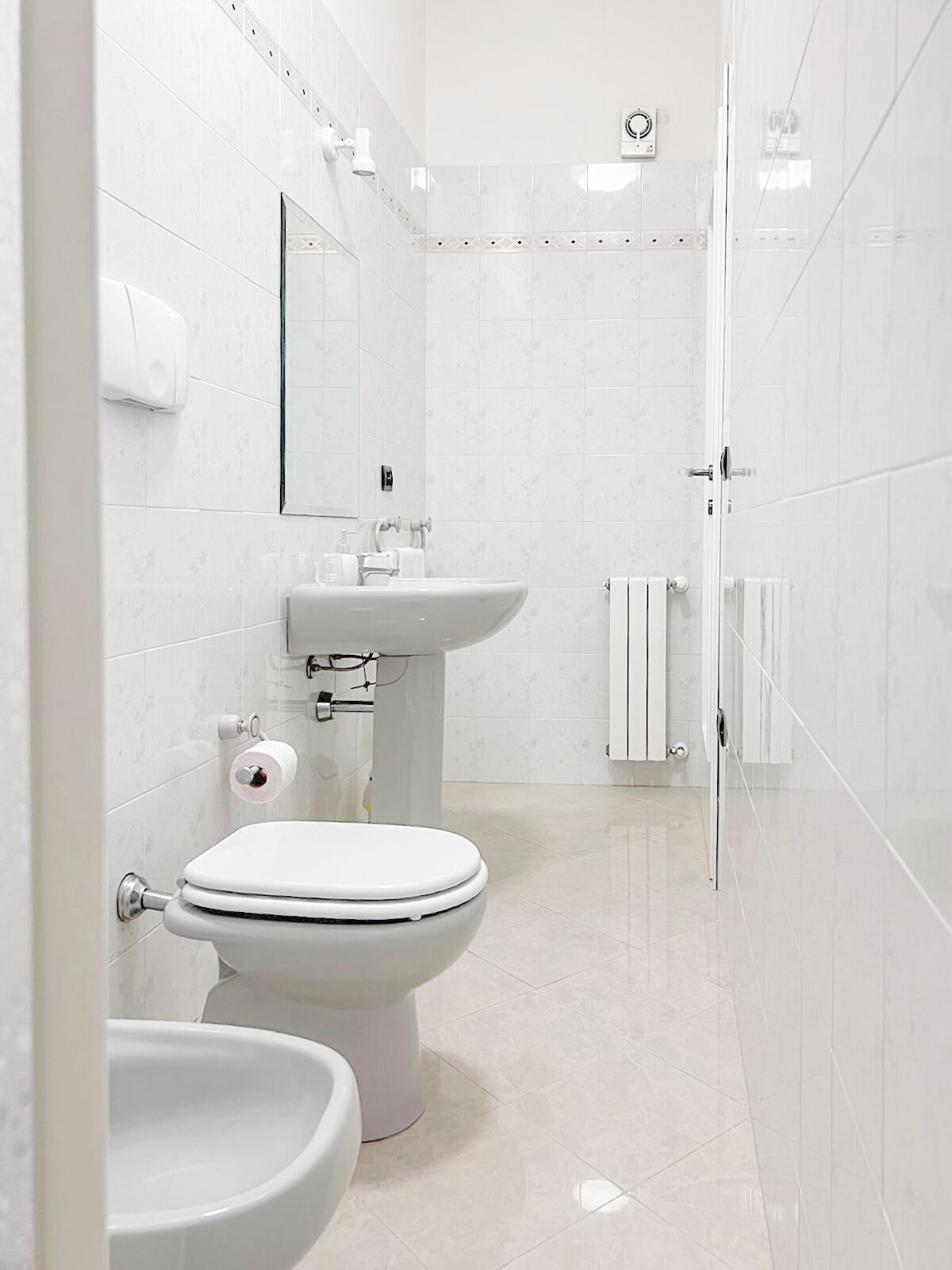 Un baño moderno con inodoro, bidé y lavamanos, todo en color blanco.