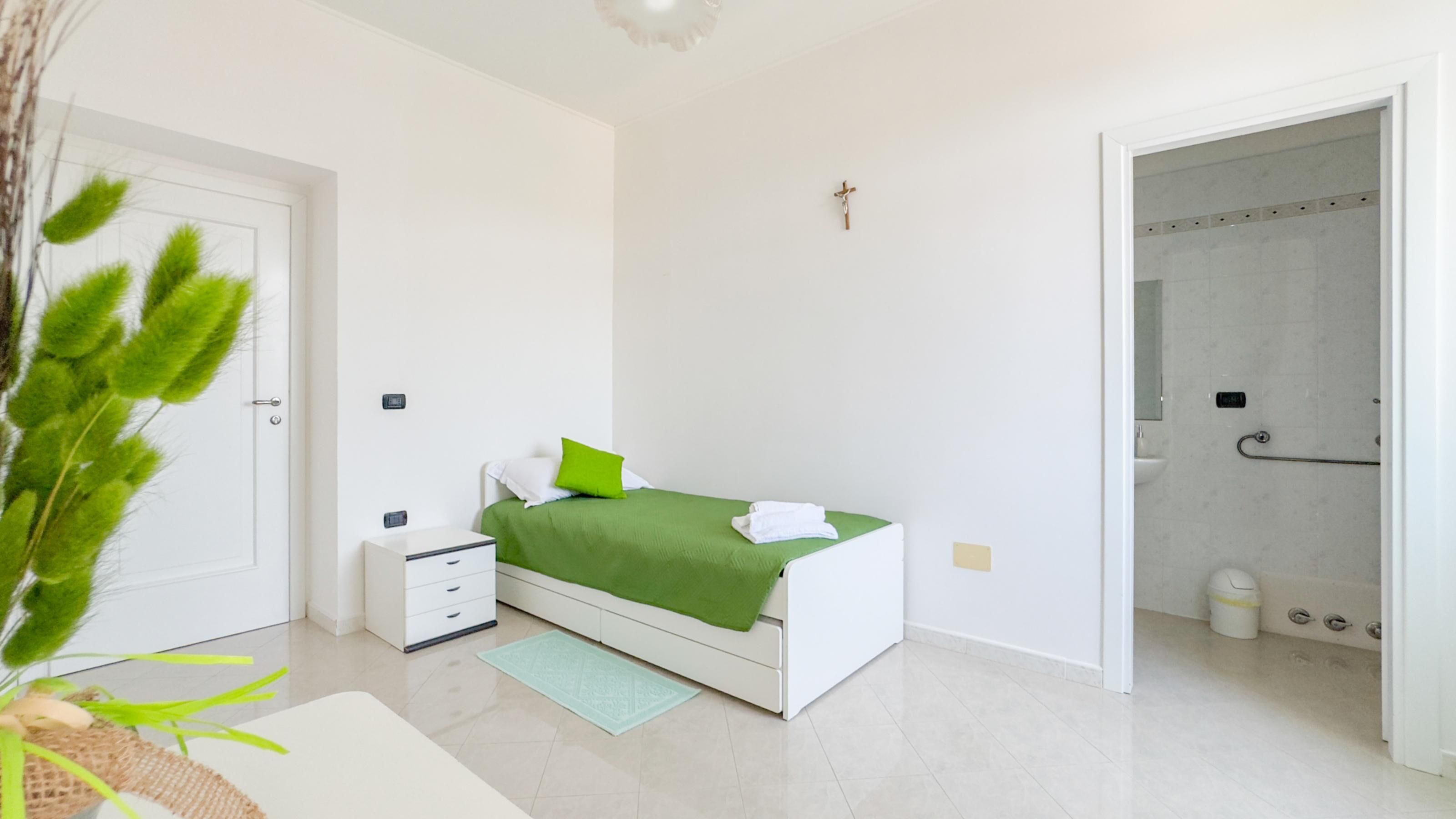 A modern bedroom with a bed, bedside table, and a green throw blanket.