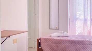Una camera da letto con un letto, un comodino, uno specchio e una porta.