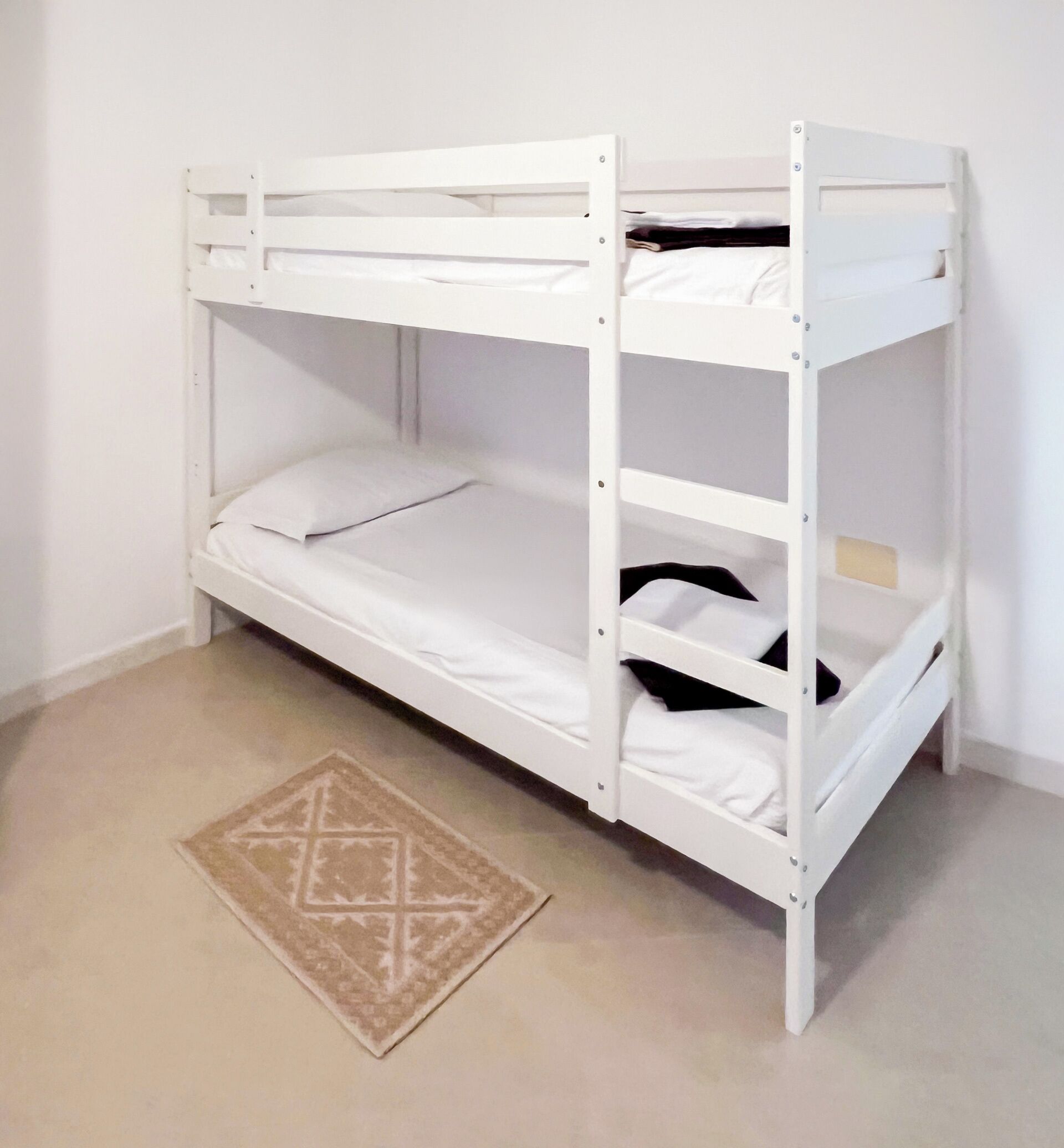 Een stapelbed met wit beddengoed en een rug met een patroon.