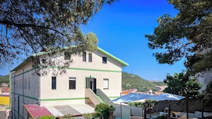 A two-story building with a green roof, a small outdoor area with a pool, and a staircase leading to the upper floor. - Ostello Brebei Niedda (Gonnesa)