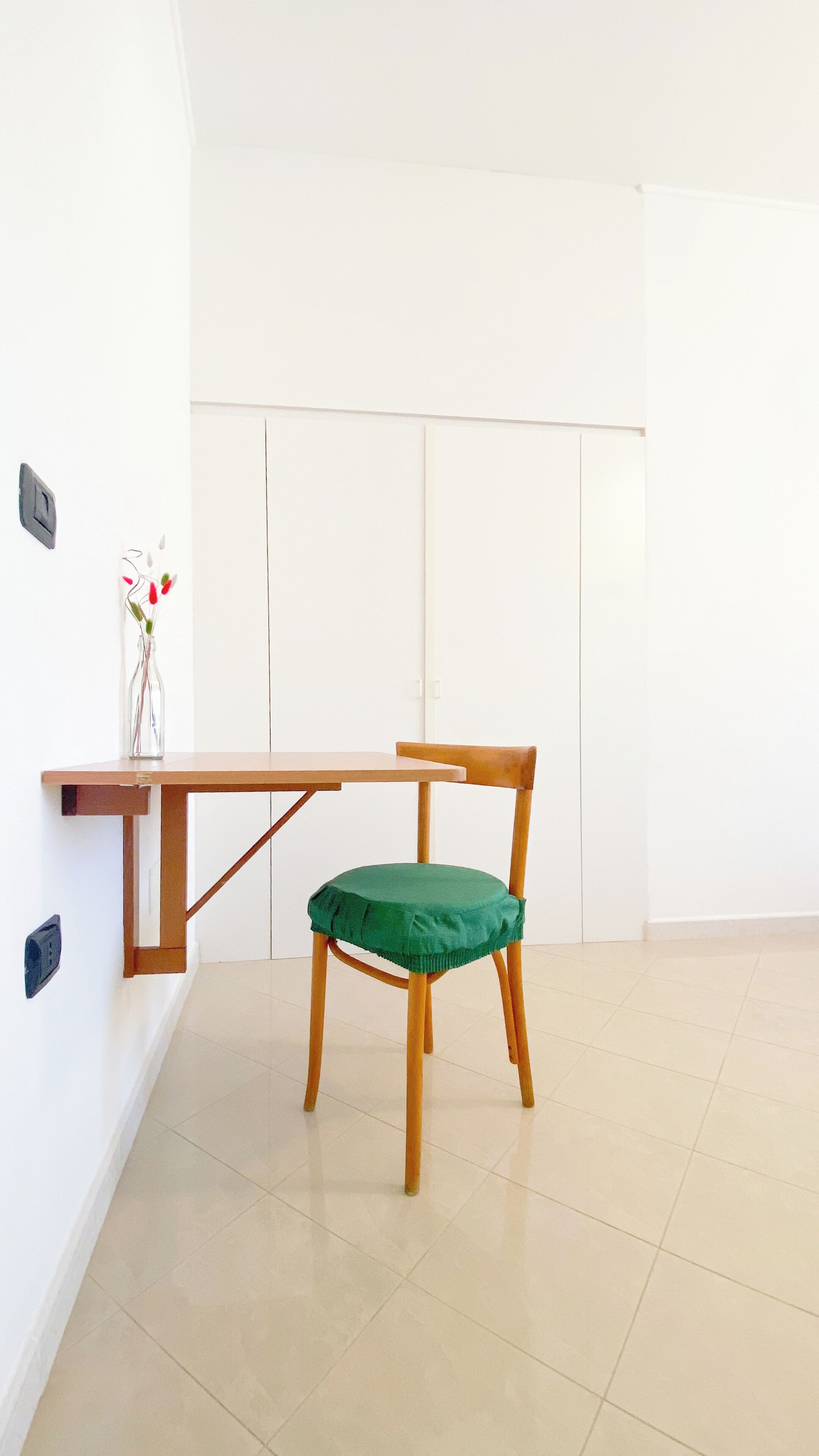 Een kamer met een houten tafel en een groene fauteuil.