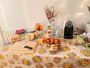 A breakfast table with pastries, fruits, and a coffee maker. - Ostello Brebei Niedda (Gonnesa)