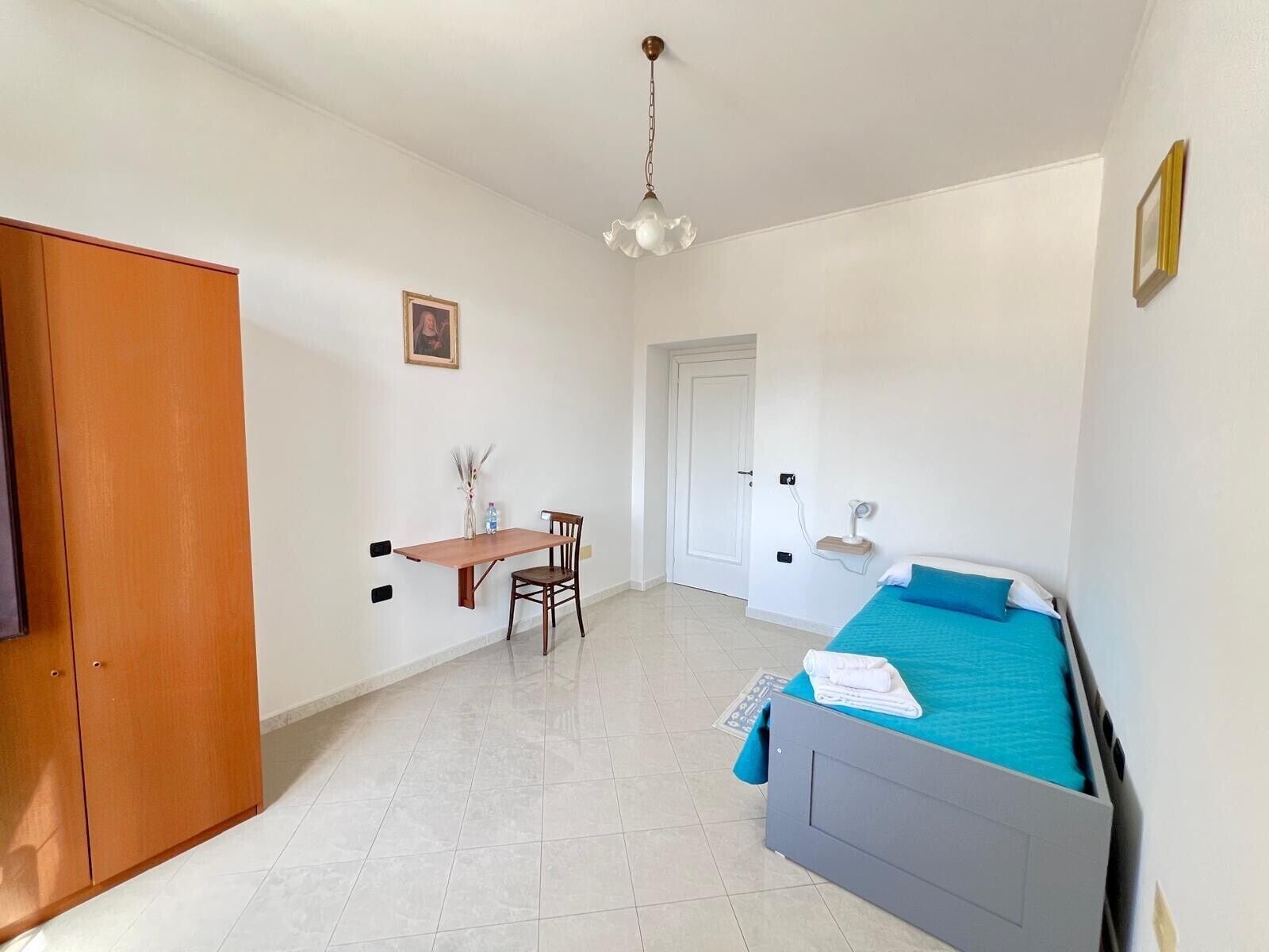 A bedroom with a bed, a desk, and a chair.