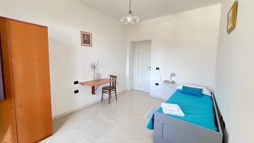 A bedroom with a bed, a desk, and a chair.