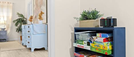 Een kamer met een blauwe boekenkast vol gezelschapsspellen, een lichtblauwe dressoir en een schilderij aan de muur.