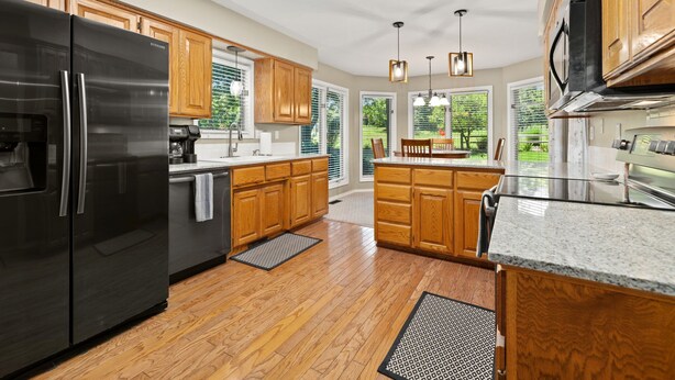 Una cocina moderna con armarios de madera, refrigerador de acero inoxidable, encimeras de granito y una isla grande.