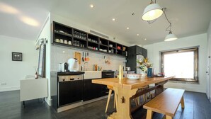 A modern kitchen with a central island, black cabinetry, and a large window providing natural light.