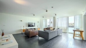 A modern living room with a grey sofa, a wooden side table, and a flat-screen TV.