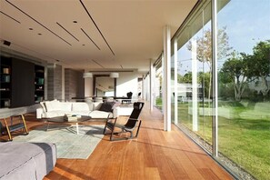 Un salon moderne doté d’une grande baie vitrée, d’un parquet en bois et de meubles contemporains.