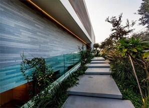 A modern building with a glass facade, a concrete pathway, and surrounding greenery. - Carmelo  Treasure Villa (Herzliya)