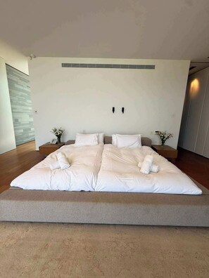 Une chambre moderne avec un grand lit, deux tables de chevet et un luminaire fixé au mur.