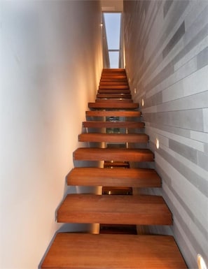 A modern staircase with wooden steps and a glass railing, leading to a higher floor. - Carmelo  Treasure Villa (Herzliya)