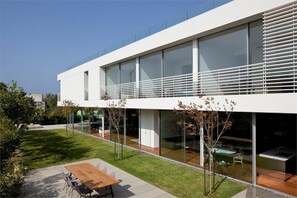 A modern building with large windows, a flat roof, and a well-maintained lawn. - Carmelo  Treasure Villa (Herzliya)