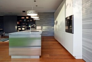 A modern kitchen with a central island, pendant lighting, and a built-in oven.