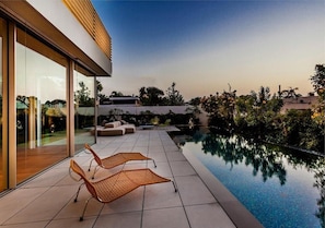 A modern outdoor pool area with lounge chairs and a glass-enclosed patio. - Carmelo  Treasure Villa (Herzliya)