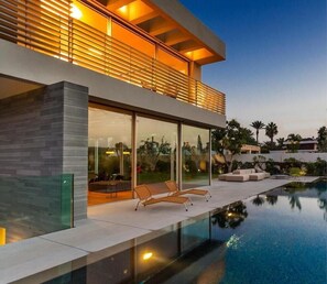 A modern house with a swimming pool, large windows, and outdoor seating.