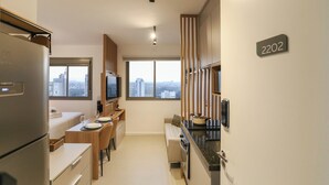 Una cocina moderna con horno empotrado, un comedor con mesa y sillas, un sofá y un amplio ventanal con vista a la ciudad.