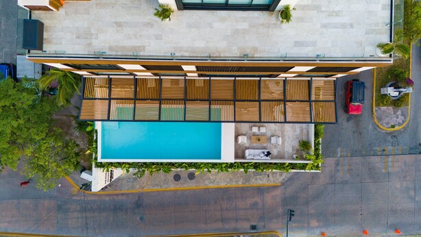 A rooftop pool area with a wooden deck, a swimming pool, and outdoor seating. - Cozumel NEW Siesta Studio: 1BR/Wi-Fi/AC/Noise Proof/With View (Cozumel)
