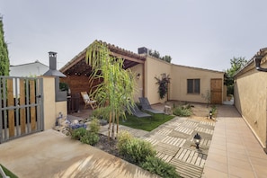 Un patio con pérgola, mobiliario exterior y un pequeño jardín.