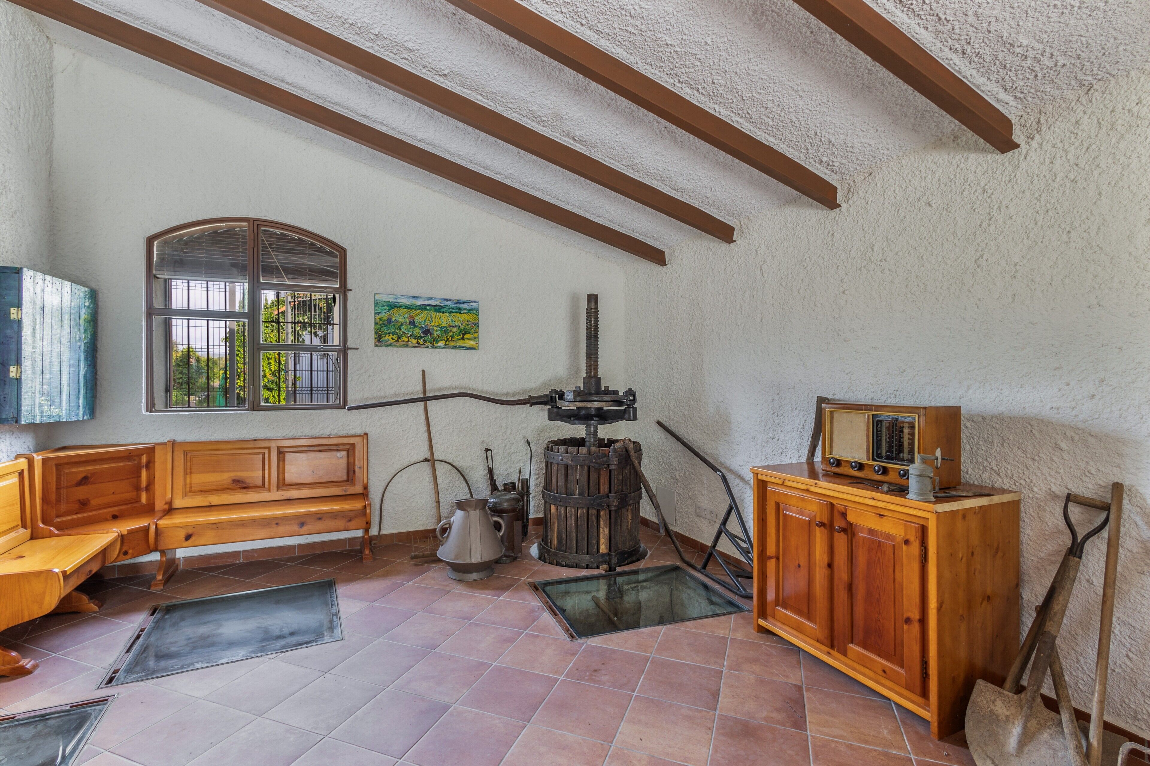 A room with a wooden bench, a window with a view, a radiator, and a cabinet.