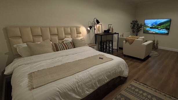 A bedroom with a large bed, a desk with two chairs, a TV, and a sofa. - Cozy room in lovely with side yard in Riyadh with WiF (Riyadh)