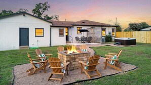 Un jardin avec un foyer extérieur, du mobilier de jardin et un jacuzzi.
