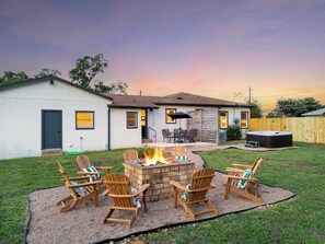 Ein Garten mit Feuerstelle, Sitzgelegenheiten im Freien und einem Whirlpool.