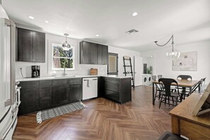 Una cocina moderna con armarios oscuros, una isla central y un comedor con mesa y sillas.