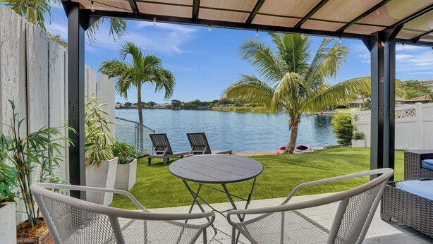 Une terrasse couverte avec vue sur une piscine et des palmiers.