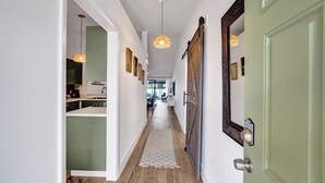 Un couloir doté d’un plancher en bois, d’un tapis à motifs et de luminaires suspendus.