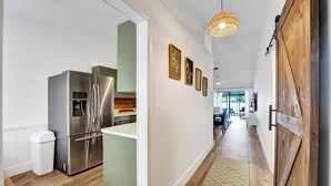 Une cuisine moderne dotée d’appareils électroménagers en acier inoxydable, d’une poubelle blanche et d’un tapis à motifs menant à un coin repas.