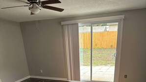 A room with dark marble flooring, a ceiling fan, and a sliding glass door leading to a backyard. - Casa confortable y de descanso. (Jacksonville)