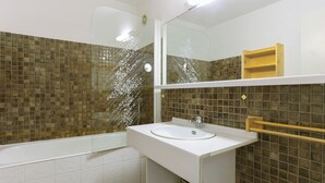 A bathroom with a white sink, a mirror, and a shower. - travelski home classic - Résidence Meijotel - Studio 4 personnes coin montagne L (Les Deux Alpes)