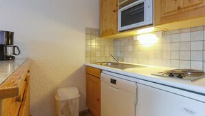 A compact kitchen with a microwave, sink, and dishwasher. - travelski home classic - Résidence Meijotel - Studio 4 personnes coin montagne L (Les Deux Alpes)