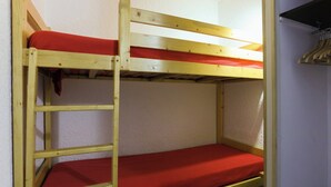 A bunk bed with a ladder, red bedding, and a wooden headboard. - travelski home classic - Résidence Meijotel - Studio 4 personnes coin montagne L (Les Deux Alpes)