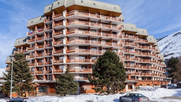 Ein mehrstöckiges Hotel mit Balkonen, umgeben von Schnee und Bäumen.