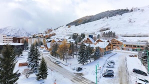 A snow-covered ski resort with wooden chalets, a main building, and a parking area.