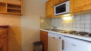 A compact kitchen with wooden cabinets, a microwave, a sink, and a dishwasher.