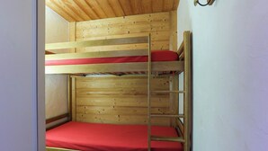 Una cama litera con estructura de madera y ropa de cama roja.