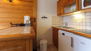 Una cocina compacta con armarios de madera, un microondas, un lavabo y una cafetera.
