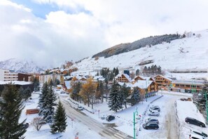 Ein schneebedecktes Skiresort mit Holzhäusern, einem Hauptgebäude und einem Parkplatz.