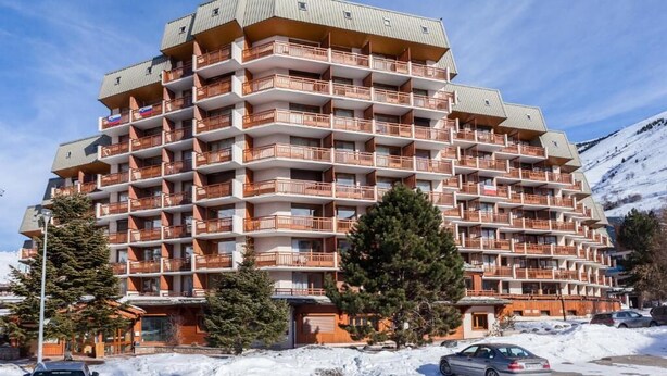 Un hotel de varios pisos con balcones, rodeado de nieve y árboles.