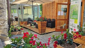 An outdoor seating area with wooden planters and chairs, a glass door entrance, and a wooden wall with a map poster. - Casa Priula (Albaredo per San Marco)