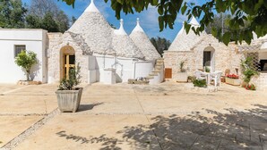 A courtyard with stone buildings, a central seating area, and potted plants. - Trulli Isabella by Wonderful Italy (Ceglie Messapica)