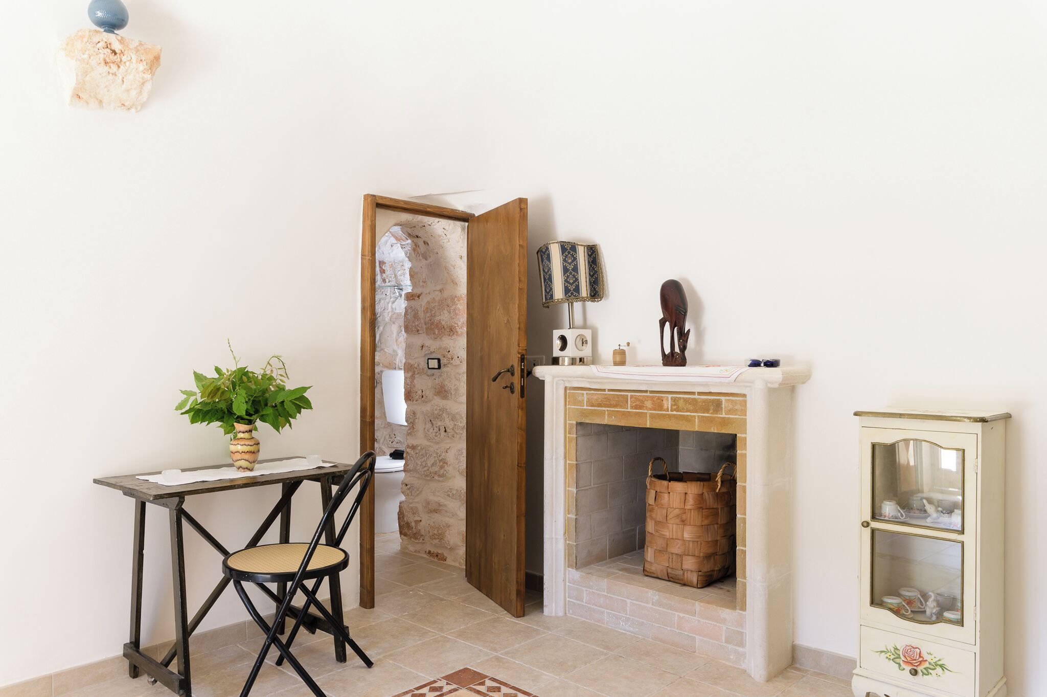 A room with a wooden table, a chair, a potted plant, a fireplace, and a cabinet.