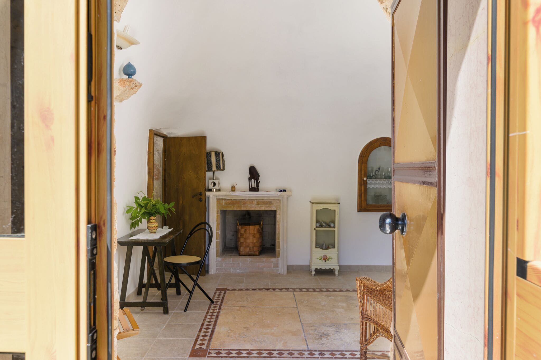 Una habitación acogedora con chimenea, una mesa de comedor con sillas, un mueble pequeño y una silla de mimbre.